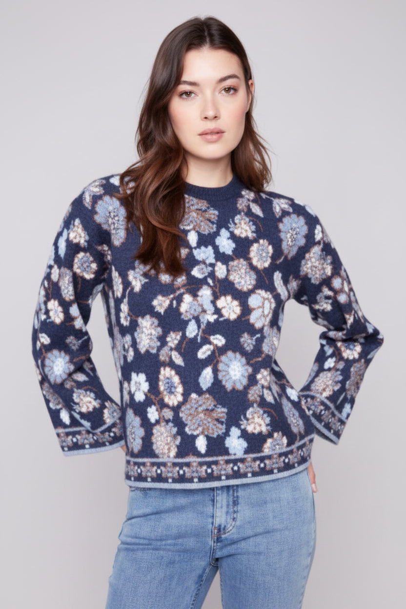 Woman wearing a navy blue floral patterned sweater against a plain background