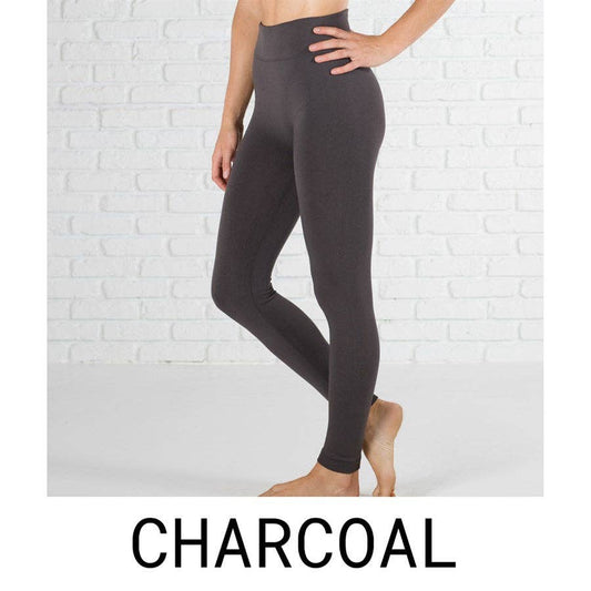 Person wearing charcoal gray leggings against a white brick wall.