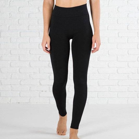 Person wearing black leggings against a white brick wall.
