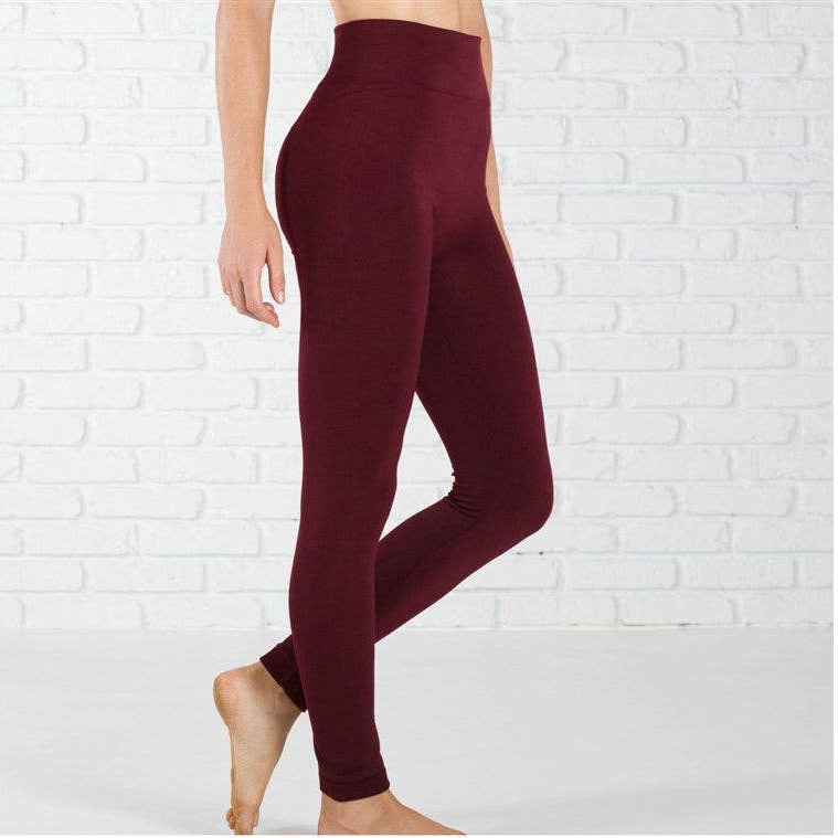 Burgundy leggings worn by a person against a white brick wall.
