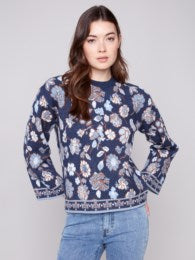 Woman wearing a navy blue floral patterned sweater against a plain background