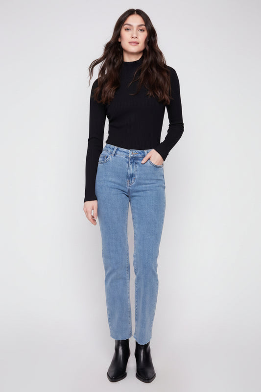 Woman wearing a black top and blue jeans on a white background