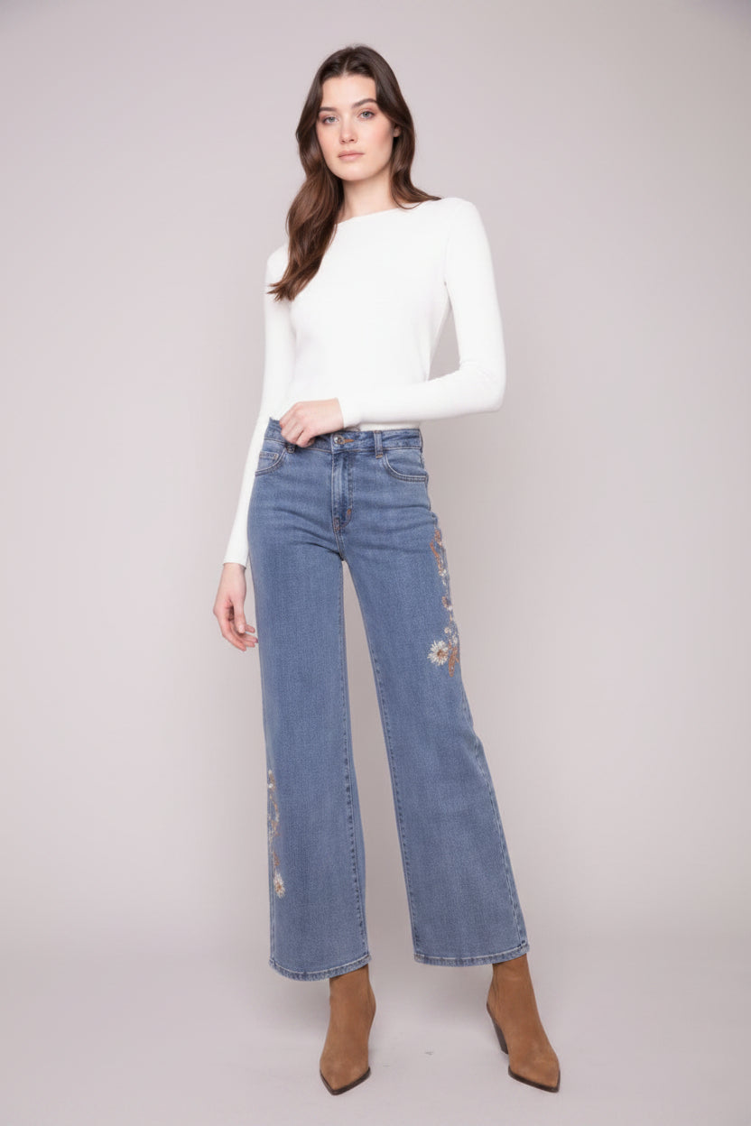 Woman wearing a white top and blue jeans on a plain background