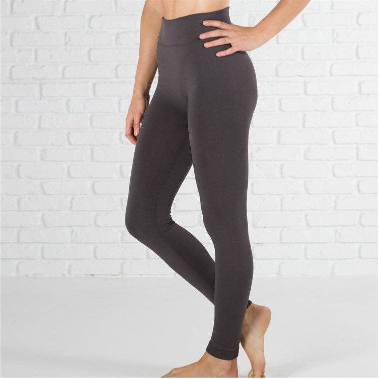 Person wearing charcoal gray leggings against a white brick wall.