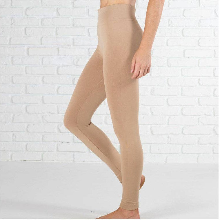 Khaki leggings worn by a person on a white brick wall background