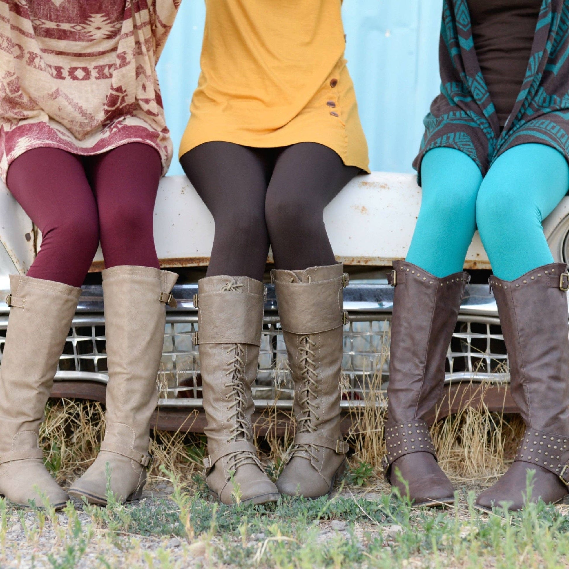 Three people wearing knee-high boots and colorful tights sitting on a vehicle.